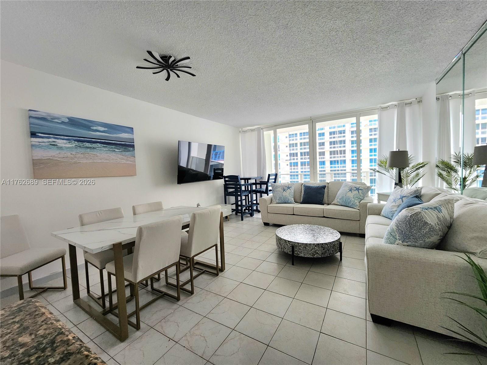A living and dining area features white tile floors, a marble-topped table, and a beige sofa — 3505 S Ocean Dr # 819, Hollywood FL 33019, HOLLYWOOD, FL