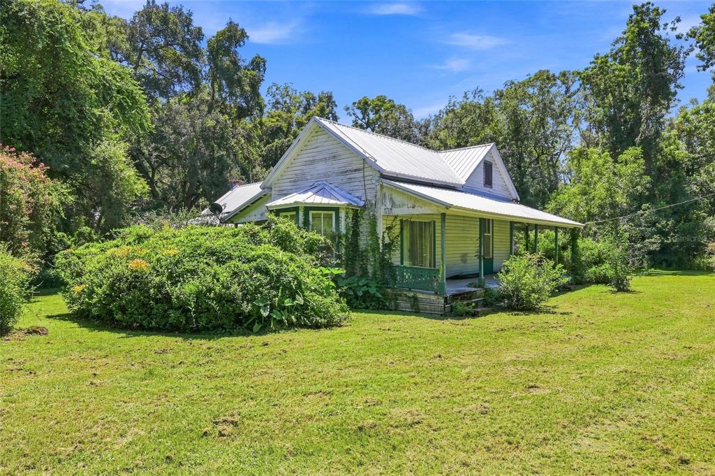 A weathered white farmhouse with a metal roof and a front porch sits on grass — 459 SW BIGFOOT COURT, FORT WHITE, FL
