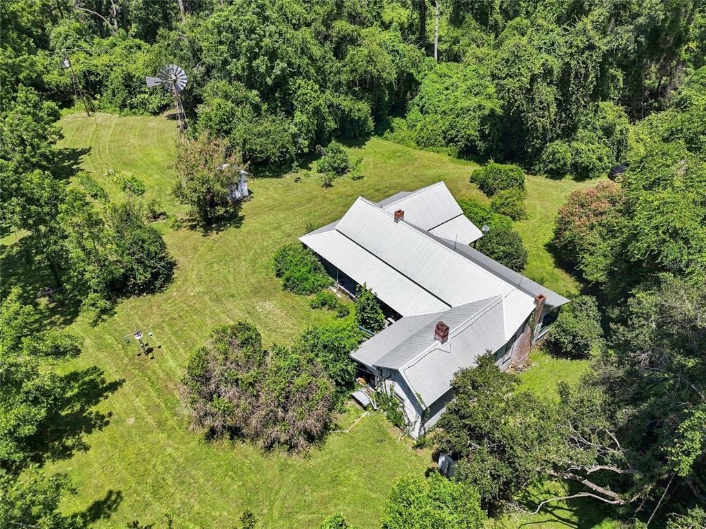 An aerial view shows a house with a metal roof, a windmill, and surrounding trees — 459 SW BIGFOOT COURT, FORT WHITE, FL