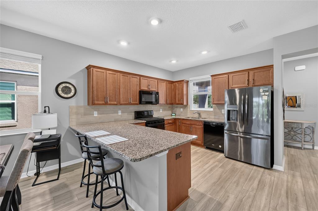 A kitchen with wood cabinets, granite countertops, stainless steel appliances, and a breakfast bar — 7909 SW 89TH CIRCLE, OCALA, FL