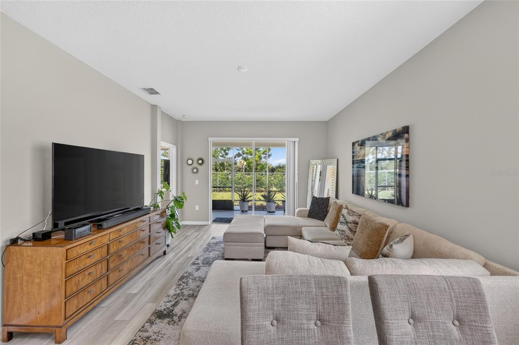 A living room features a large sectional sofa, a wooden media console, and sliding glass doors — 7909 SW 89TH CIRCLE, OCALA, FL