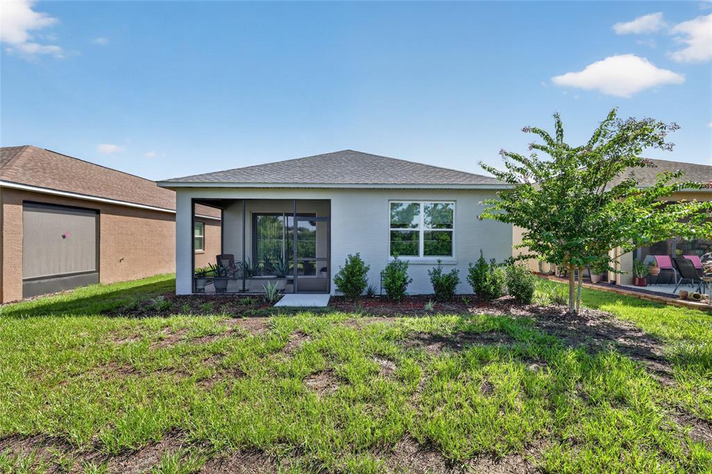 The rear exterior of a single-story house features a screened-in porch and a small tree — 7909 SW 89TH CIRCLE, OCALA, FL