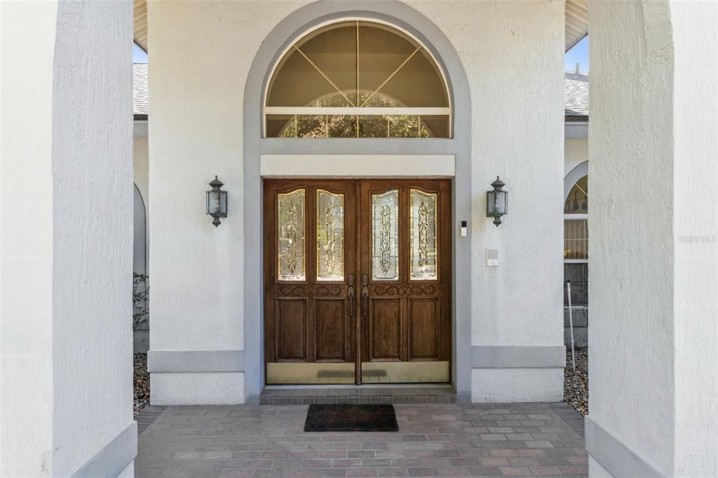 A front entryway features double wooden doors with glass panels under an arched transom window — 2964 PLANTATION ROAD, WINTER HAVEN, FL