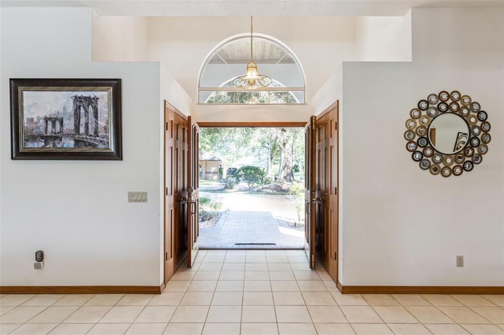 An entryway with tile flooring, double wooden doors, a large arched window, and wall decor — 2964 PLANTATION ROAD, WINTER HAVEN, FL