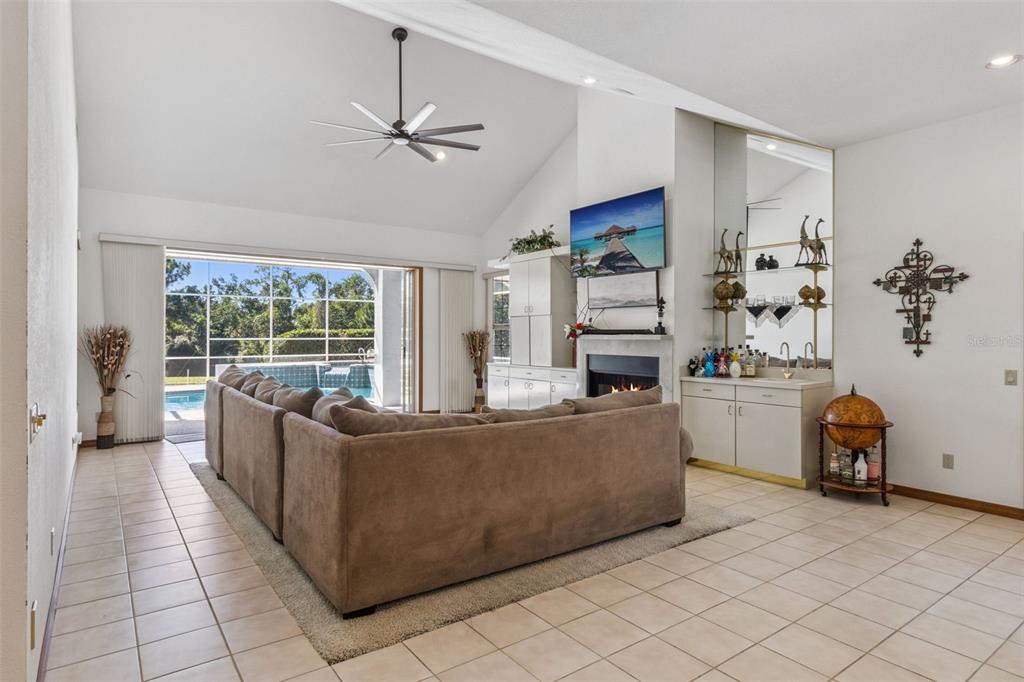 A living room features a vaulted ceiling, a fireplace, a wet bar, and sliding glass doors — 2964 PLANTATION ROAD, WINTER HAVEN, FL