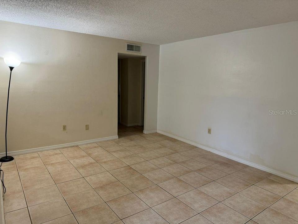 An empty room with beige tile flooring, white walls, and a doorway leading to another area — 700 E AIRPORT BOULEVARD UNIT B7, SANFORD, FL