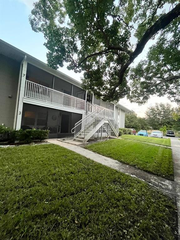 A two-story apartment building features a white metal staircase leading to an upper balcony — 700 E AIRPORT BOULEVARD UNIT B7, SANFORD, FL