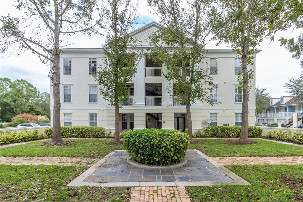 A three-story apartment building with a central staircase and a landscaped front yard — 233 GOLDENRAIN DRIVE UNIT 202, CELEBRATION, FL