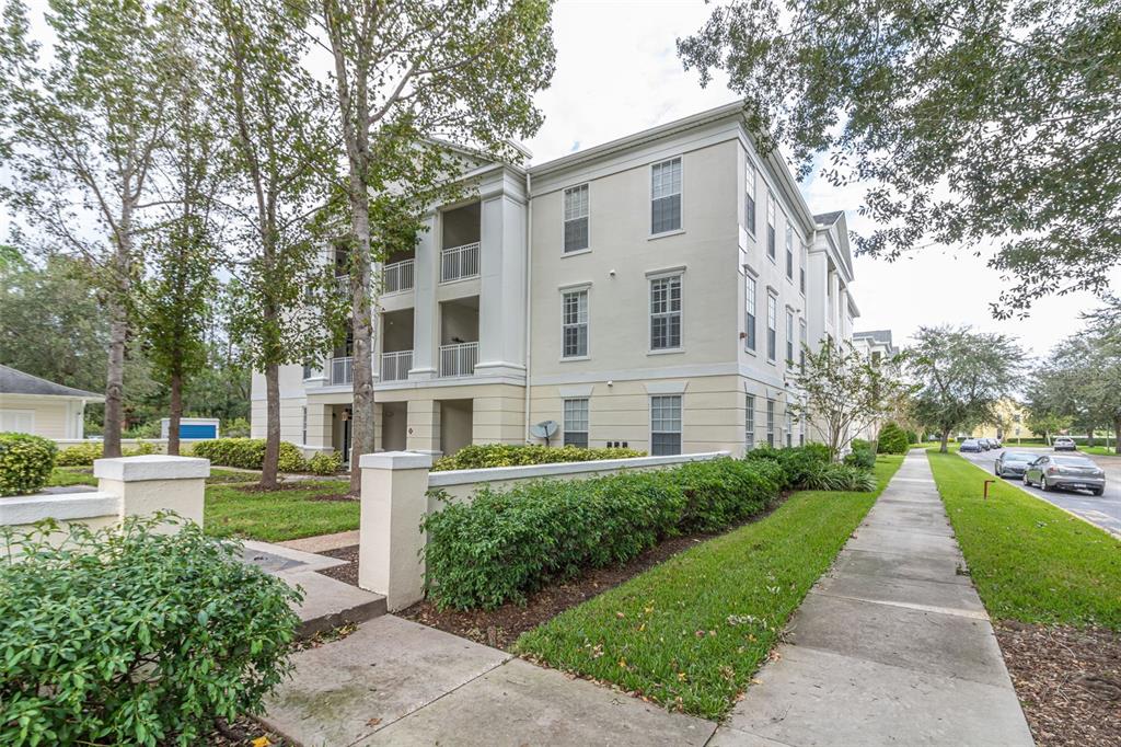 A multi-story apartment building with balconies and a sidewalk along a landscaped lawn — 233 GOLDENRAIN DRIVE UNIT 202, CELEBRATION, FL
