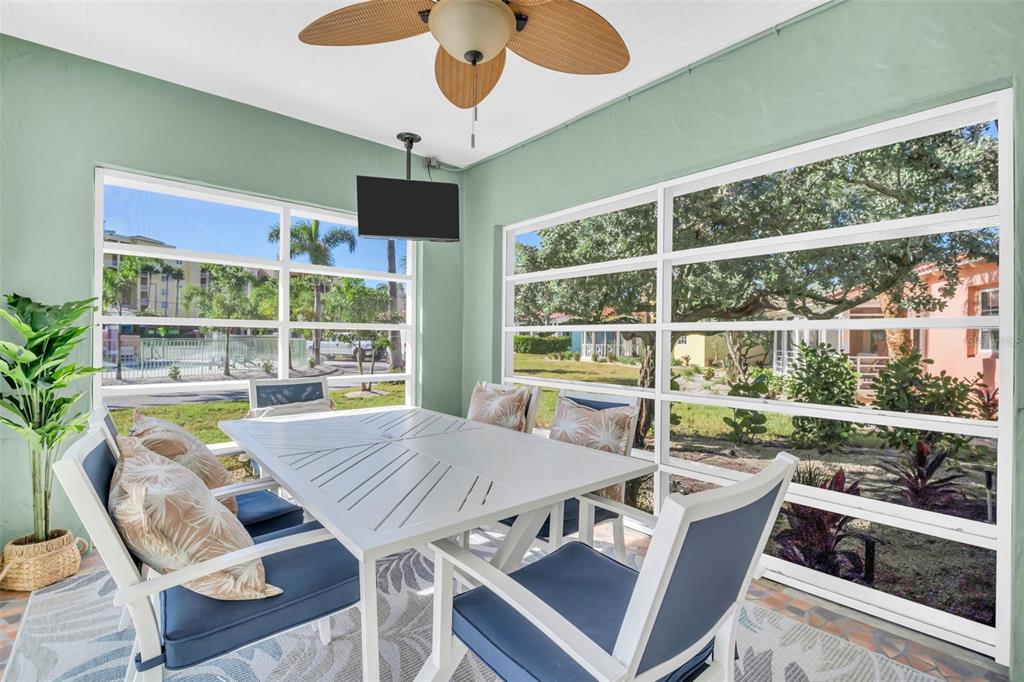 A sunroom features a white dining set, a ceiling fan, and large windows overlooking landscaping — 16613 GULF BOULEVARD, NORTH REDINGTON BEACH, FL
