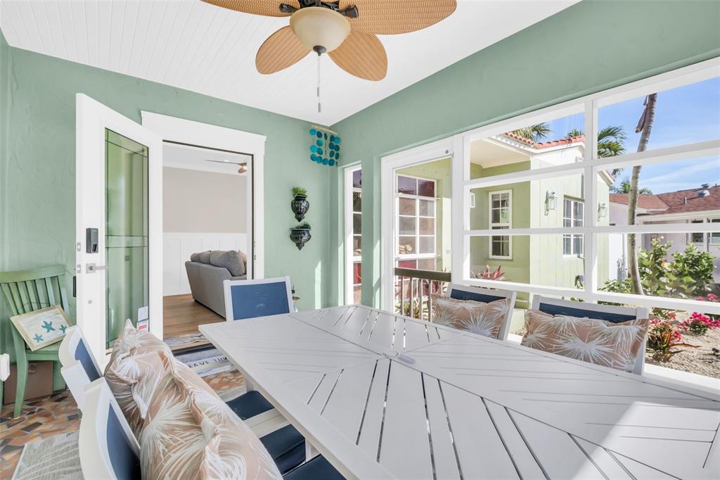 A sunroom features a white dining table, green walls, a ceiling fan, and large windows — 16613 GULF BOULEVARD, NORTH REDINGTON BEACH, FL