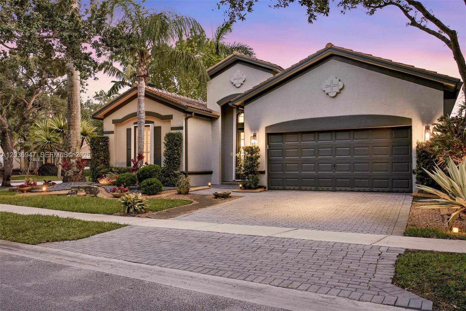 A single-story house with a paved driveway, a two-car garage, and landscaped front yard — 19308 Stonebrook St, Weston FL 33332, WESTON, FL