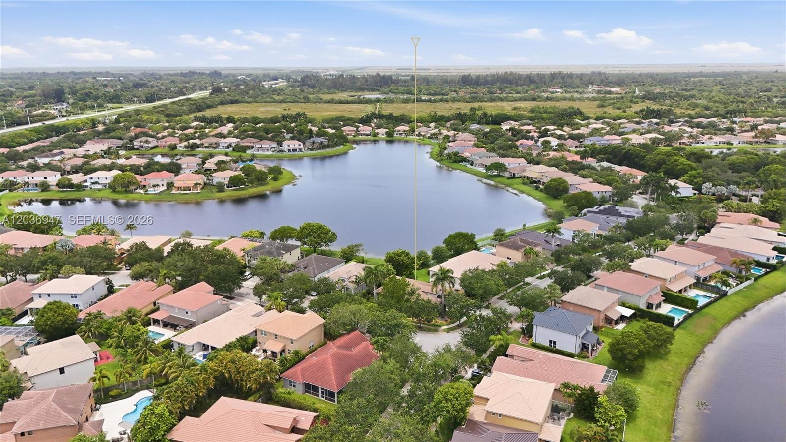 An aerial view shows a suburban neighborhood with houses surrounding a large central lake — 19308 Stonebrook St, Weston FL 33332, WESTON, FL