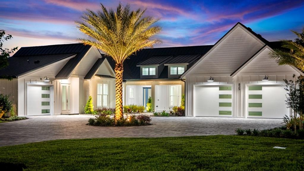 A modern white house with a metal roof, three garage doors, and a palm tree — 825 PHEASANT RUN COURT W, PORT ORANGE, FL
