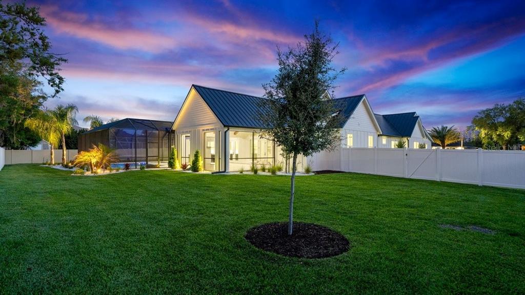 A white house with a metal roof and a fenced backyard at sunset — 825 PHEASANT RUN COURT W, PORT ORANGE, FL