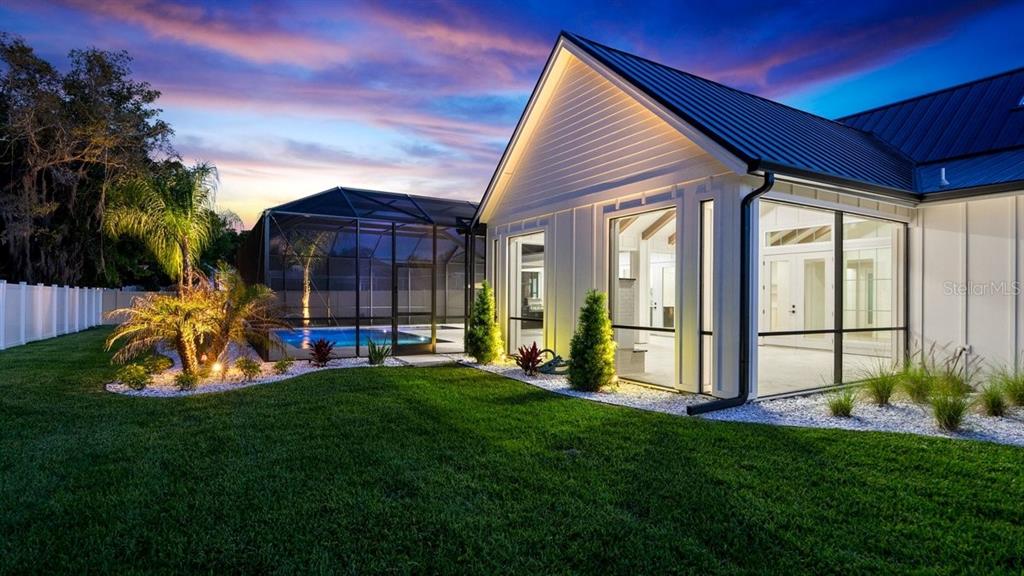 A white house with a metal roof and a screened-in pool in the backyard — 825 PHEASANT RUN COURT W, PORT ORANGE, FL
