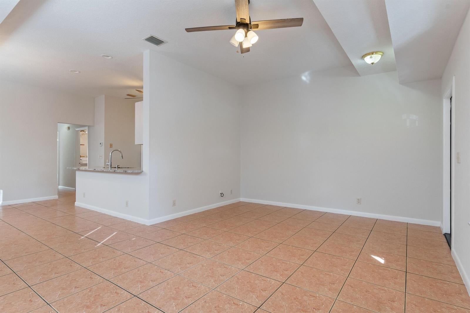 An empty living room features light-colored walls, a ceiling fan, and orange-toned tile flooring — 623 N L Street, FL 33460, FL