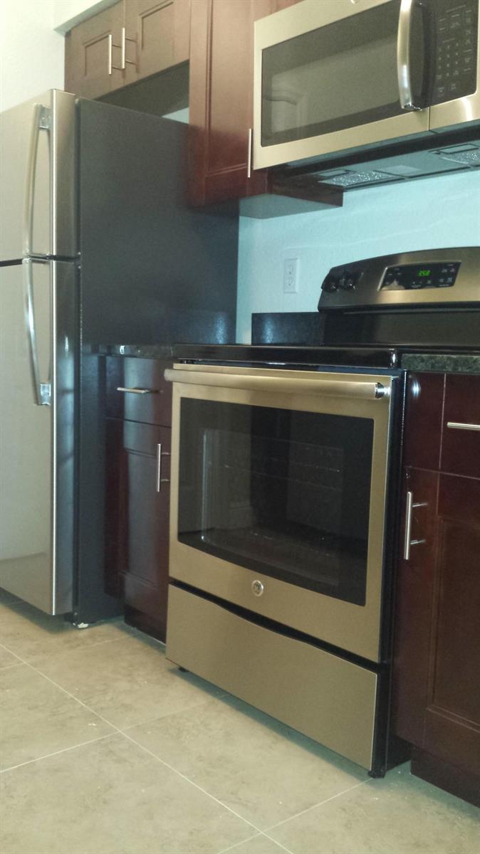 A kitchen features dark wood cabinets, stainless steel appliances, and light-colored tile flooring — 1708 Belmont Place # 1708, Boynton Beach FL 33436, BOYNTON BEACH, FL