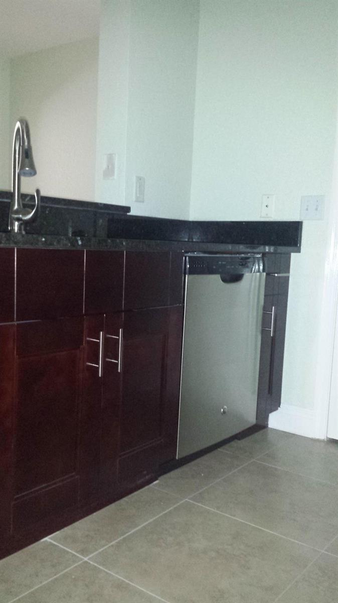 A kitchen features dark wood cabinets, a stainless steel dishwasher, and a black countertop — 1708 Belmont Place # 1708, Boynton Beach FL 33436, BOYNTON BEACH, FL