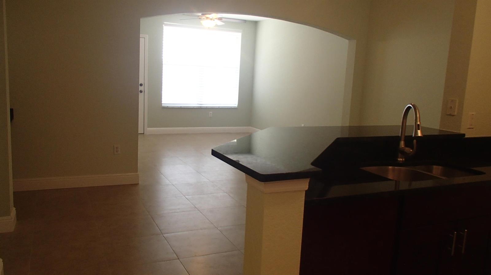 A kitchen island with a dark countertop and sink overlooks an adjacent living area — 1708 Belmont Place # 1708, Boynton Beach FL 33436, BOYNTON BEACH, FL