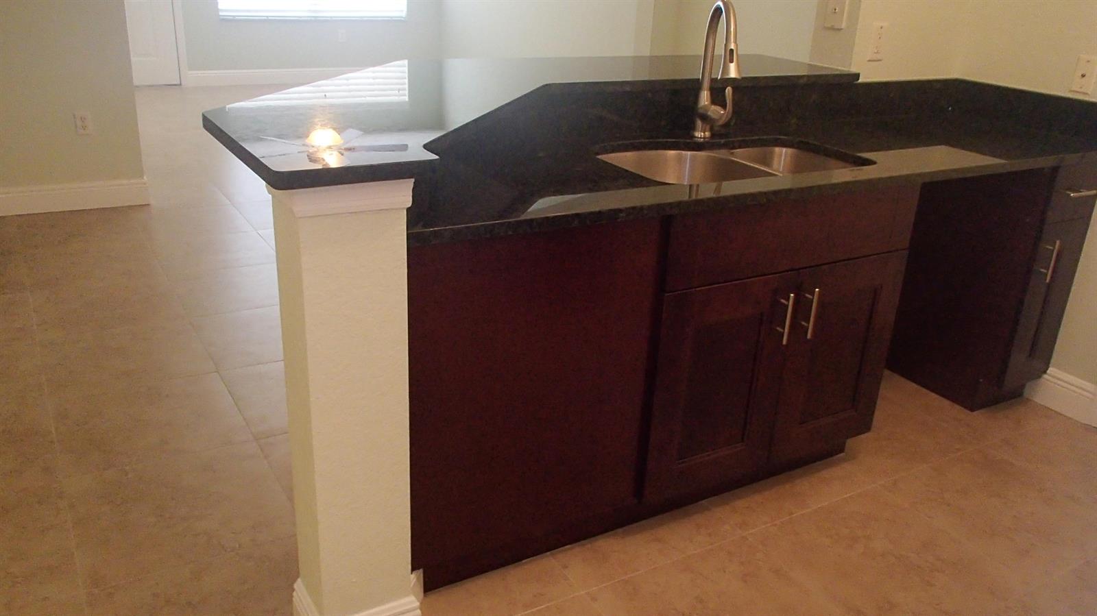 A kitchen island with a dark countertop, stainless steel sink, and dark wood cabinetry — 1708 Belmont Place # 1708, Boynton Beach FL 33436, BOYNTON BEACH, FL