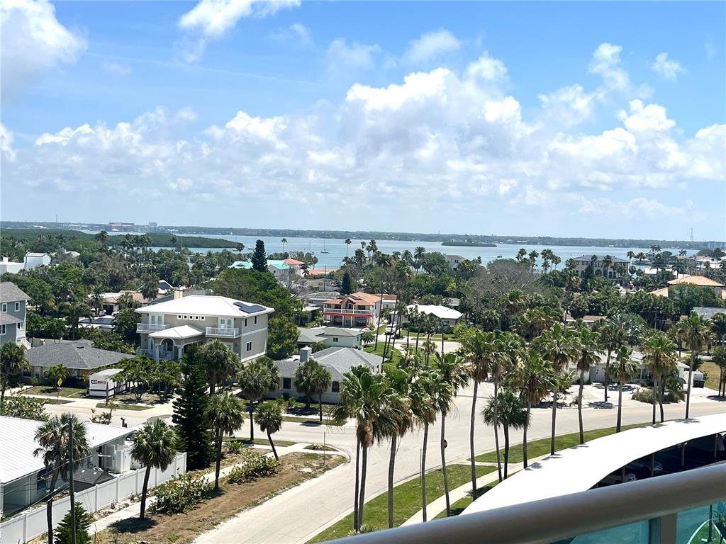 An elevated view shows a coastal neighborhood with houses, palm trees, and a distant bay — 880 MANDALAY AVENUE UNIT N610, CLEARWATER BEACH, FL