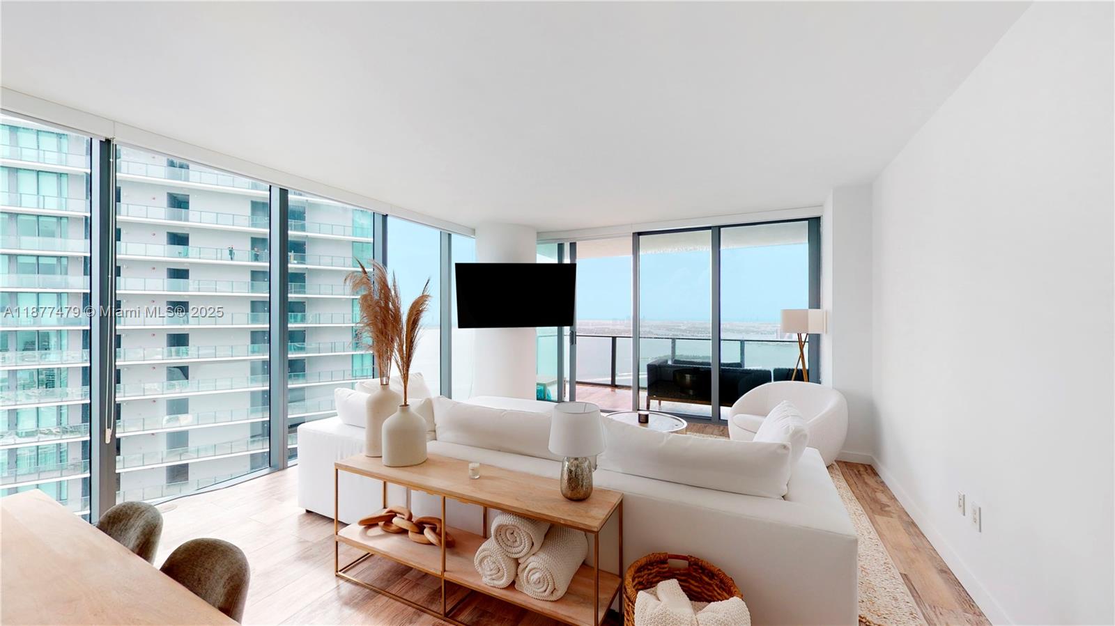 A bright living room features a white sofa, a console table, and floor-to-ceiling windows — 650 NE 32ND ST # 4607, Miami FL 33137, MIAMI, FL