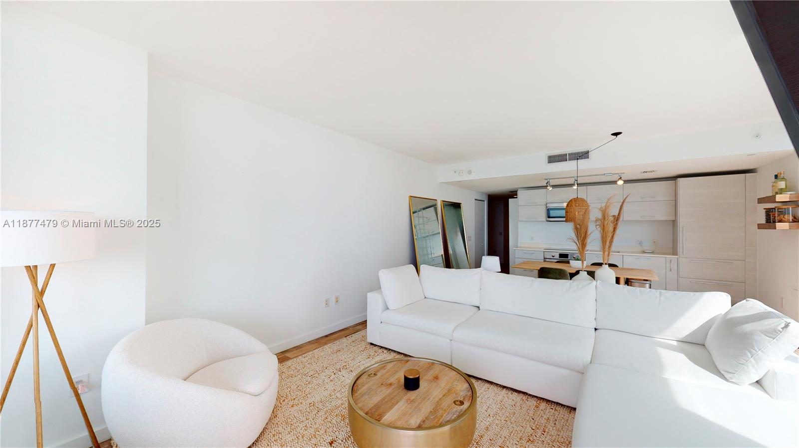 A bright living room features a white sectional sofa, a round coffee table, and an armchair — 650 NE 32ND ST # 4607, Miami FL 33137, MIAMI, FL