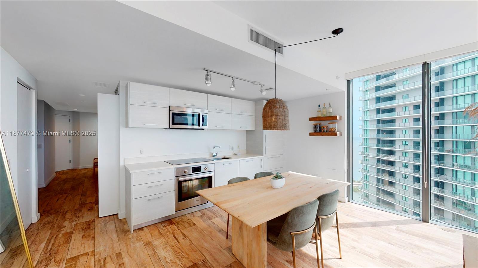 A modern kitchen and dining area features light wood floors, white cabinetry, and floor-to-ceiling windows — 650 NE 32ND ST # 4607, Miami FL 33137, MIAMI, FL