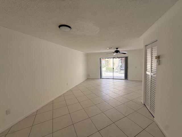 An empty living room with white walls, tile flooring, a ceiling fan, and sliding doors — 314 Waterside Drive, Hypoluxo FL 33462, HYPOLUXO, FL
