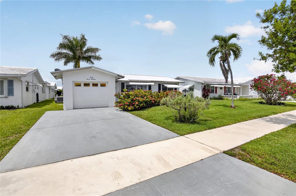 A single-story house with a white garage, concrete driveway, and palm trees on a lawn — 719 SW 18TH STREET, BOYNTON BEACH, FL