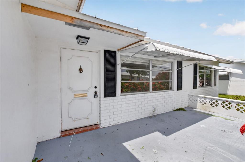 A white brick house exterior features a front door, windows with awnings, and a patio — 719 SW 18TH STREET, BOYNTON BEACH, FL