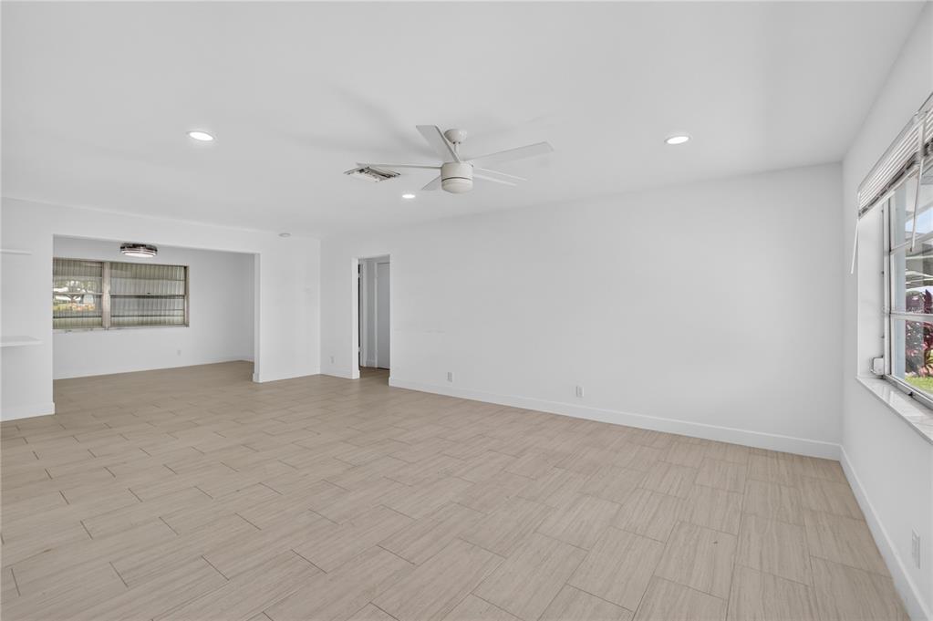 An empty living room with light wood-look tile floors, white walls, and a ceiling fan — 719 SW 18TH STREET, BOYNTON BEACH, FL