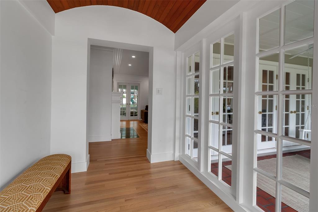 A hallway with a wood-paneled arched ceiling, hardwood floors, a bench, and glass-paned doors — 1838 ALTA VISTA STREET, SARASOTA, FL