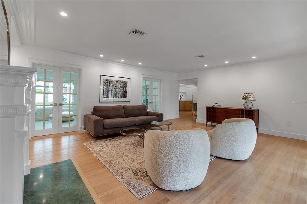 A living room features a brown sofa, two white armchairs, a patterned rug, and hardwood floors — 1838 ALTA VISTA STREET, SARASOTA, FL