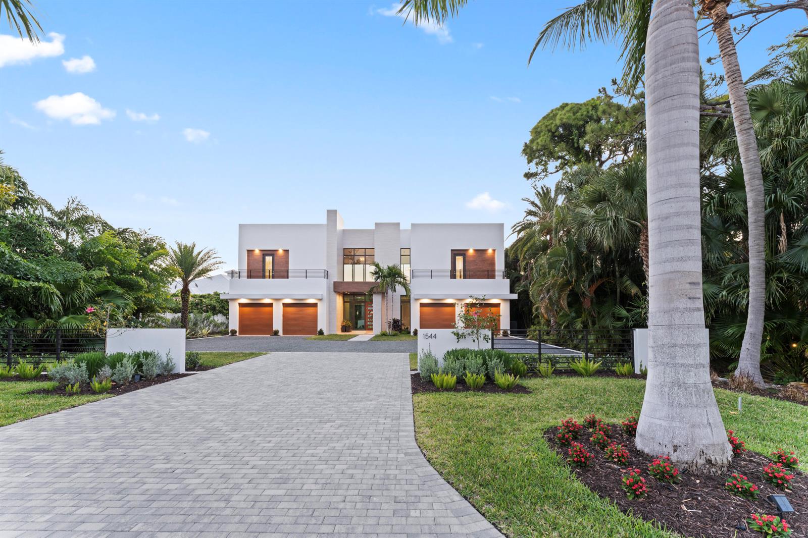 A modern two-story house with a paved driveway, four garage doors, and lush tropical landscaping — 1544 SE Saint Lucie Boulevard, Stuart FL 34996, STUART, FL