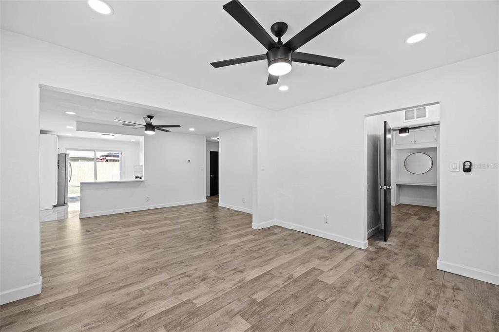 A bright, open-concept living area features white walls, wood-look flooring, and two ceiling fans — 4427 W OKLAHOMA AVENUE, TAMPA, FL