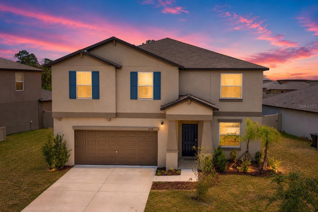 A two-story suburban house with a tan stucco exterior, blue shutters, and a two-car garage — 2139 OLD MINING ROAD, LAKELAND, FL