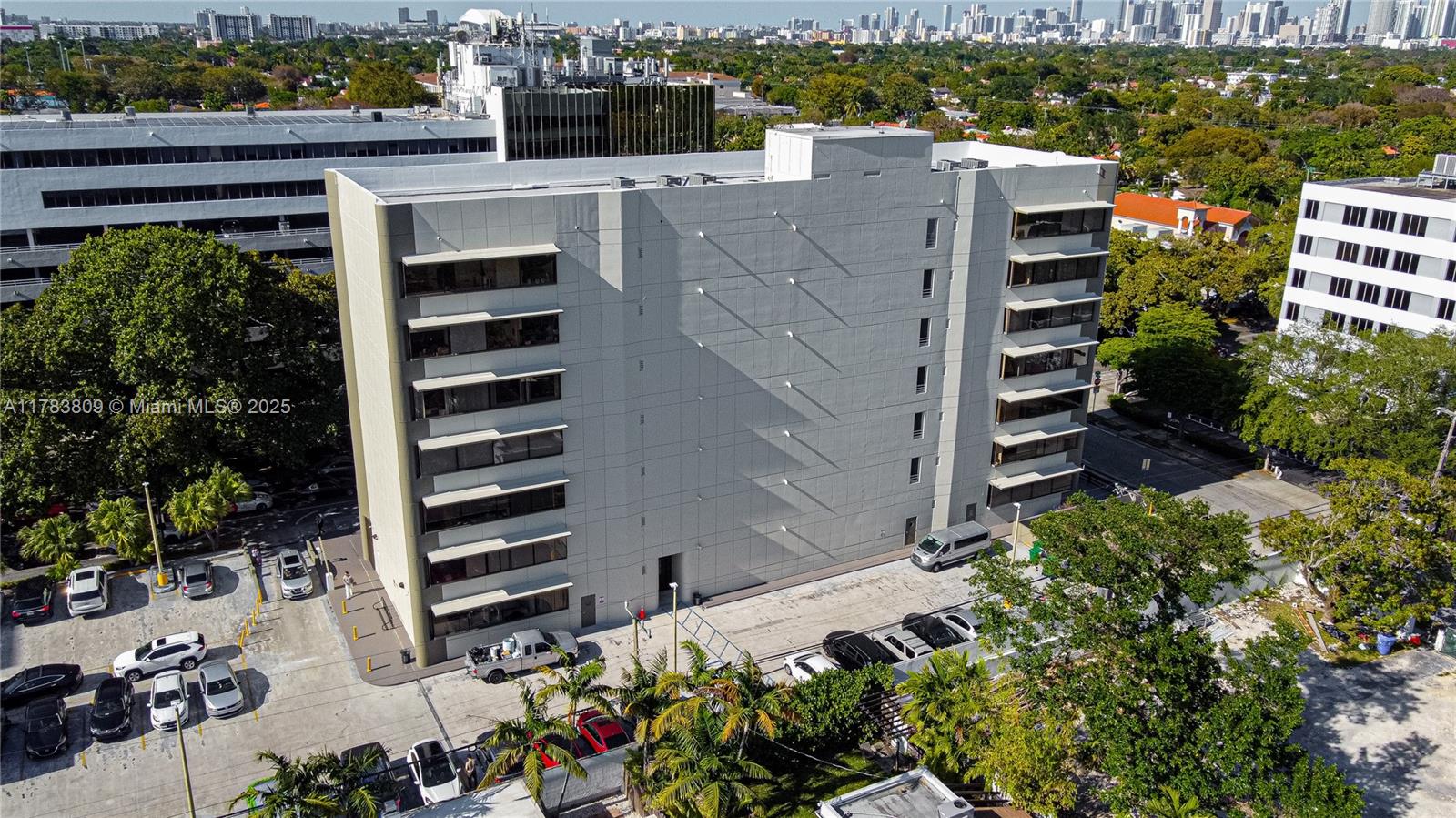 An aerial view shows a multi-story office building with a large, windowless gray facade — 2100 SW 22nd St # 302, Miami FL 33145, MIAMI, FL