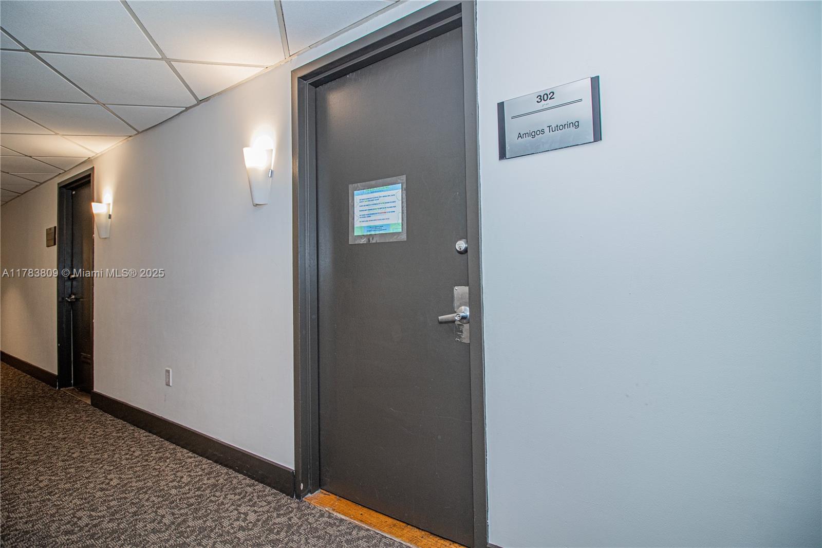 A hallway features a dark gray door labeled 302 for Amigos Tutoring with wall sconces — 2100 SW 22nd St # 302, Miami FL 33145, MIAMI, FL
