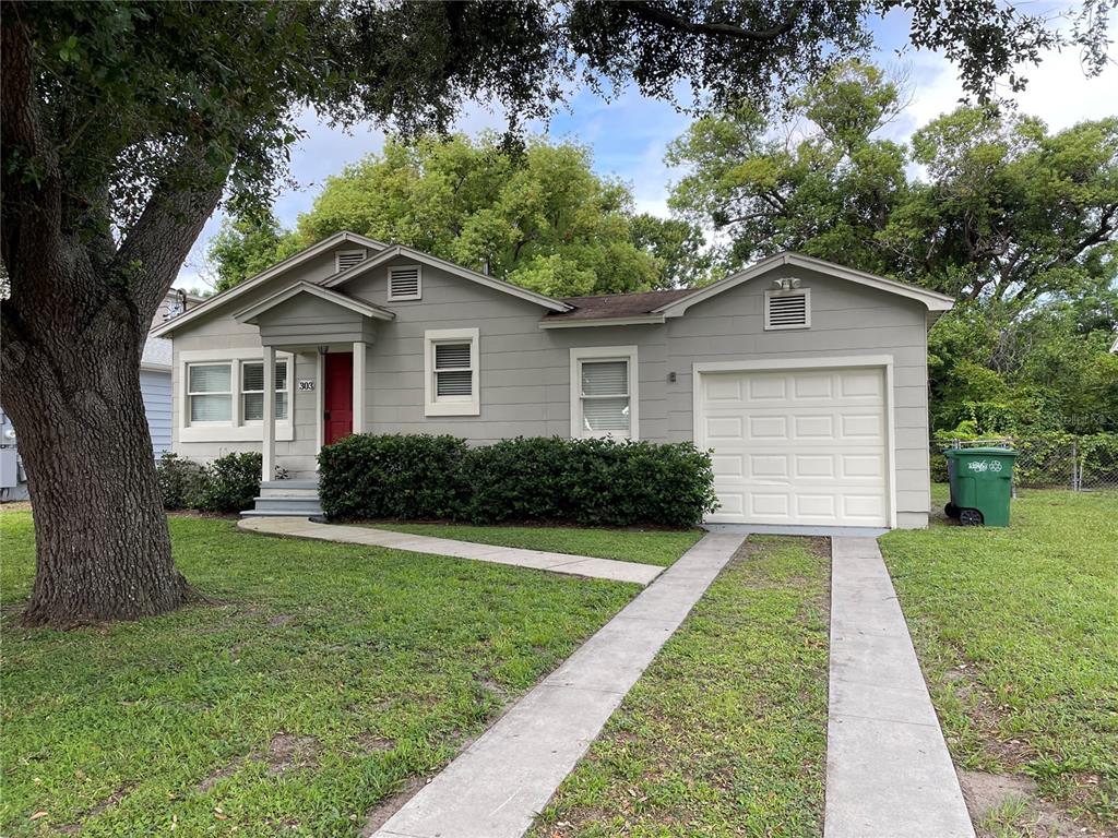 A single-story gray house with a red front door, a garage, and a concrete driveway — 303 S AUDUBON AVENUE, TAMPA, FL