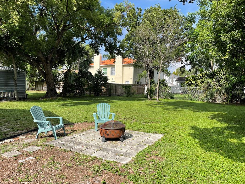 A backyard features a stone patio with a fire pit and two light blue chairs — 303 S AUDUBON AVENUE, TAMPA, FL