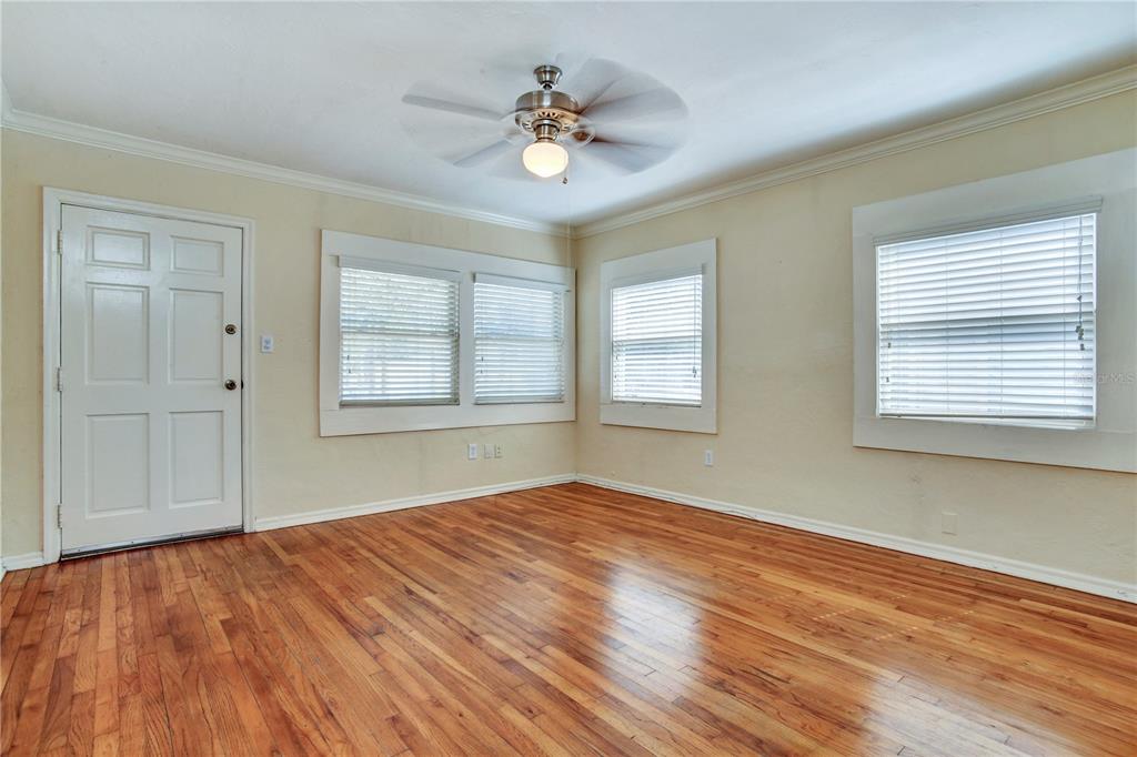 An empty room features hardwood floors, a ceiling fan, and several windows with white blinds — 303 S AUDUBON AVENUE, TAMPA, FL