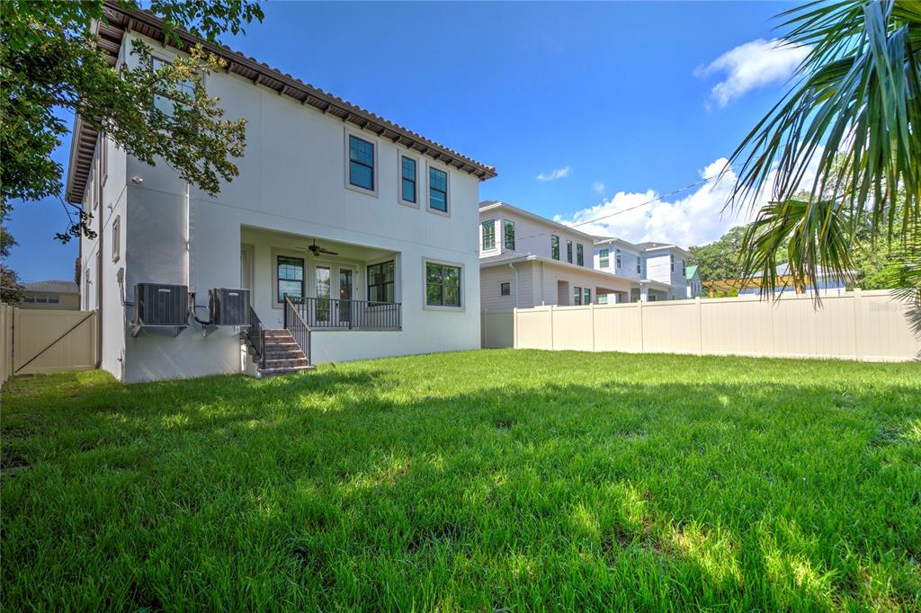The exterior rear view of a two-story house features a grassy yard and vinyl fencing — 855 39TH AVENUE N, ST PETERSBURG, FL