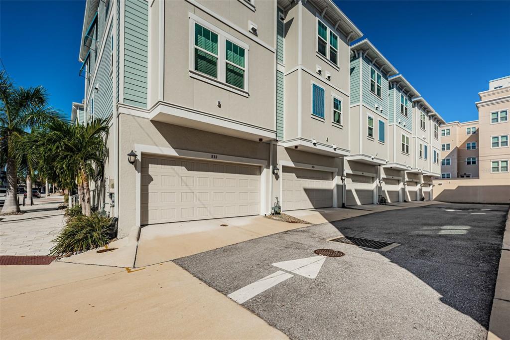 A row of multi-story townhomes with beige stucco siding and attached garages under a clear sky — 815 BURLINGTON AVENUE N, ST PETERSBURG, FL