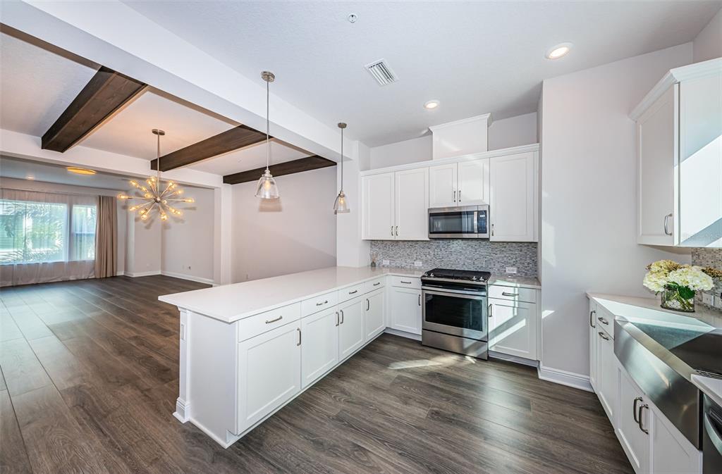 A modern kitchen features white cabinets, stainless steel appliances, and a large island with seating — 815 BURLINGTON AVENUE N, ST PETERSBURG, FL