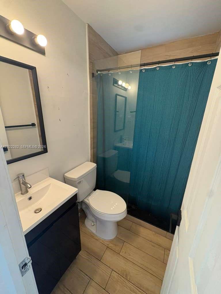 A bathroom features a vanity, a toilet, and a shower with a teal curtain — 3210 Canal Dr # 5, Pompano Beach FL 33062, POMPANO BEACH, FL