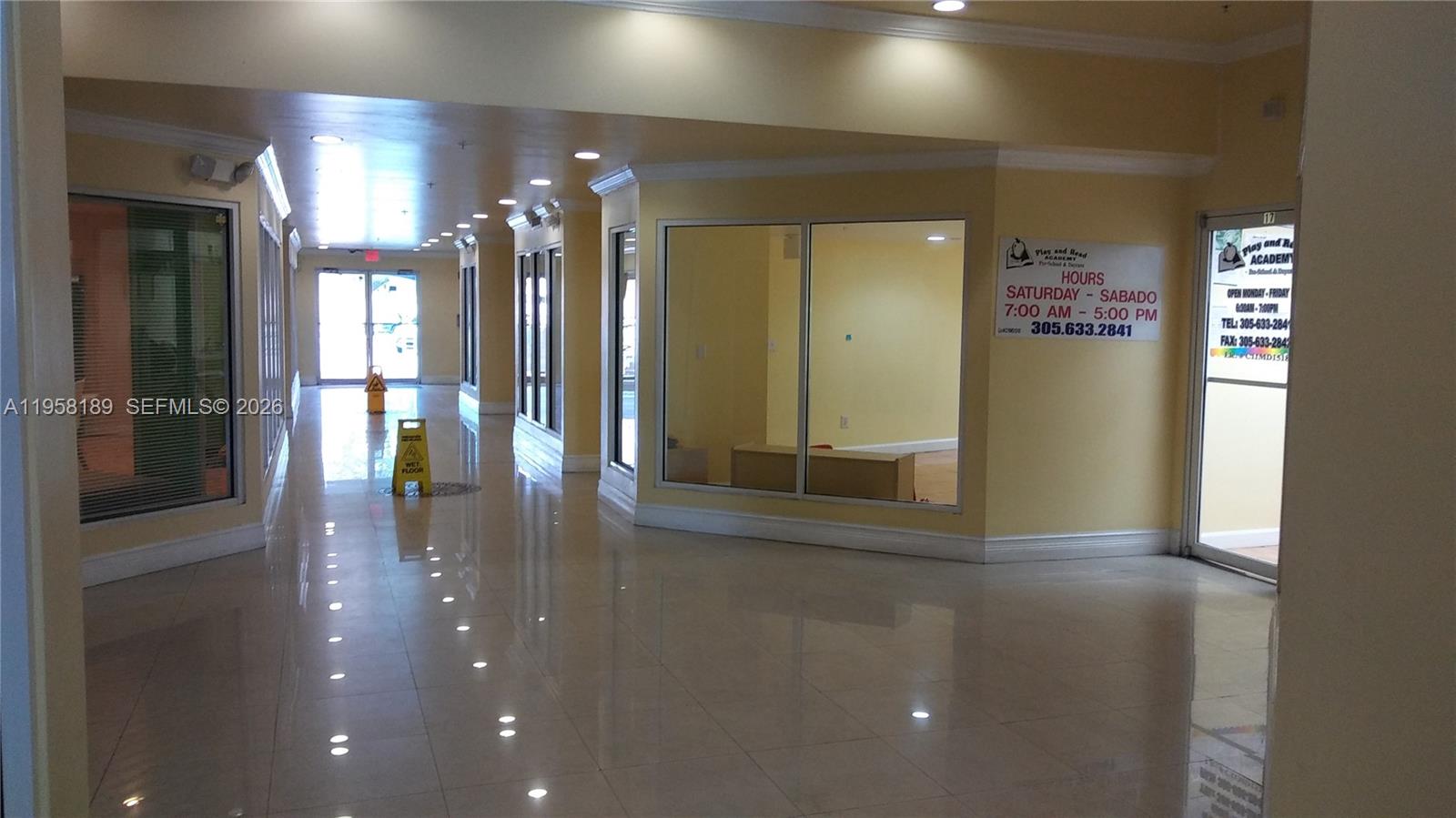 A bright, tiled hallway leads to a glass-fronted commercial space with posted business hours — 1726 NW 36th St # 2, Miami FL 33142, MIAMI, FL