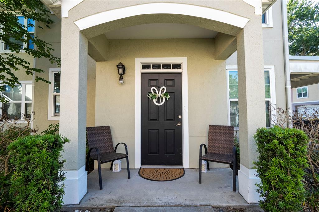 A covered front porch features a black door with a wreath and two wicker chairs — 3353 WESTCHESTER SQUARE BOULEVARD UNIT 101, ORLANDO, FL
