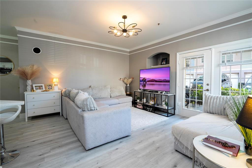 A living room features light gray flooring, a sectional sofa, and a television on a stand — 3353 WESTCHESTER SQUARE BOULEVARD UNIT 101, ORLANDO, FL